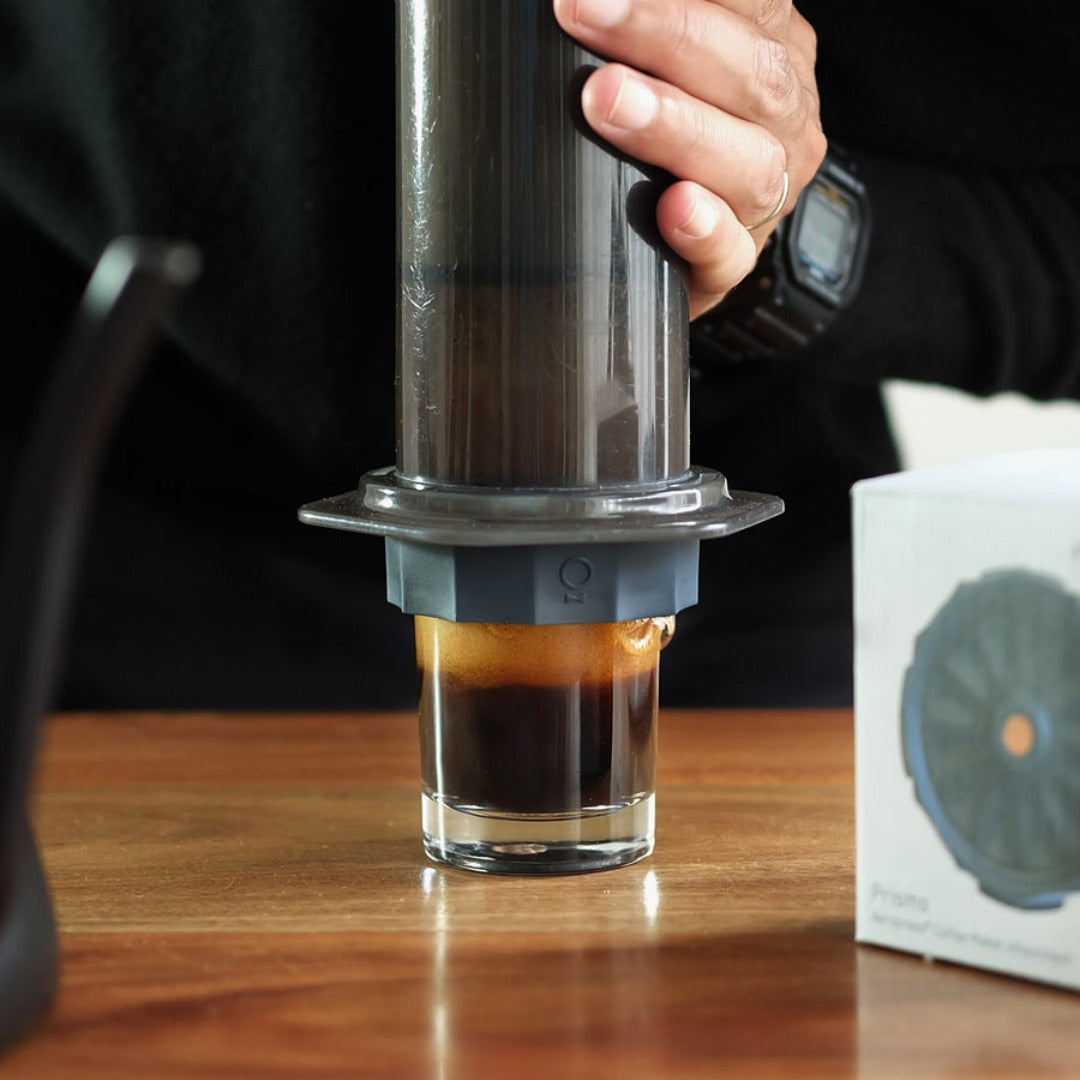Fellow Prismo Aeropress filter in use, attached and extracting coffee in a home setting.