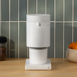 The Fellow Opus coffee grinder with a white finish set on a counterspace.