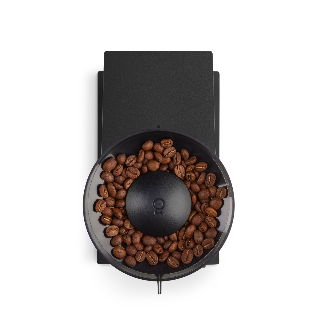 Overhead view of the Fellow Opus coffee grinder with a black finish with coffee in the hopper.