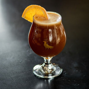 Shop Specialty Coffee Glassware tulip glass featuring images of hops and a crow in gold screenprint, with cold brew coffee and an orange slice.