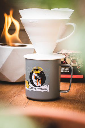 Specialty Coffee Roasters Camp Mug designed by Zaine Vaun depicting a crowned crane, with a pourover and small campfire.