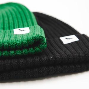 Detail of black and green wool beanies with tags depicting a crow.