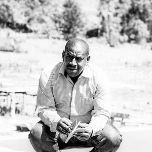 Coffee producer Venuste Mugraniza sitting holding a notebook at the Tumba Washing Station in Rwanda.