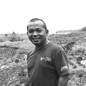 Coffee Producer Voster Hutamabarat standing in front of a coffee farm in Indonesia.