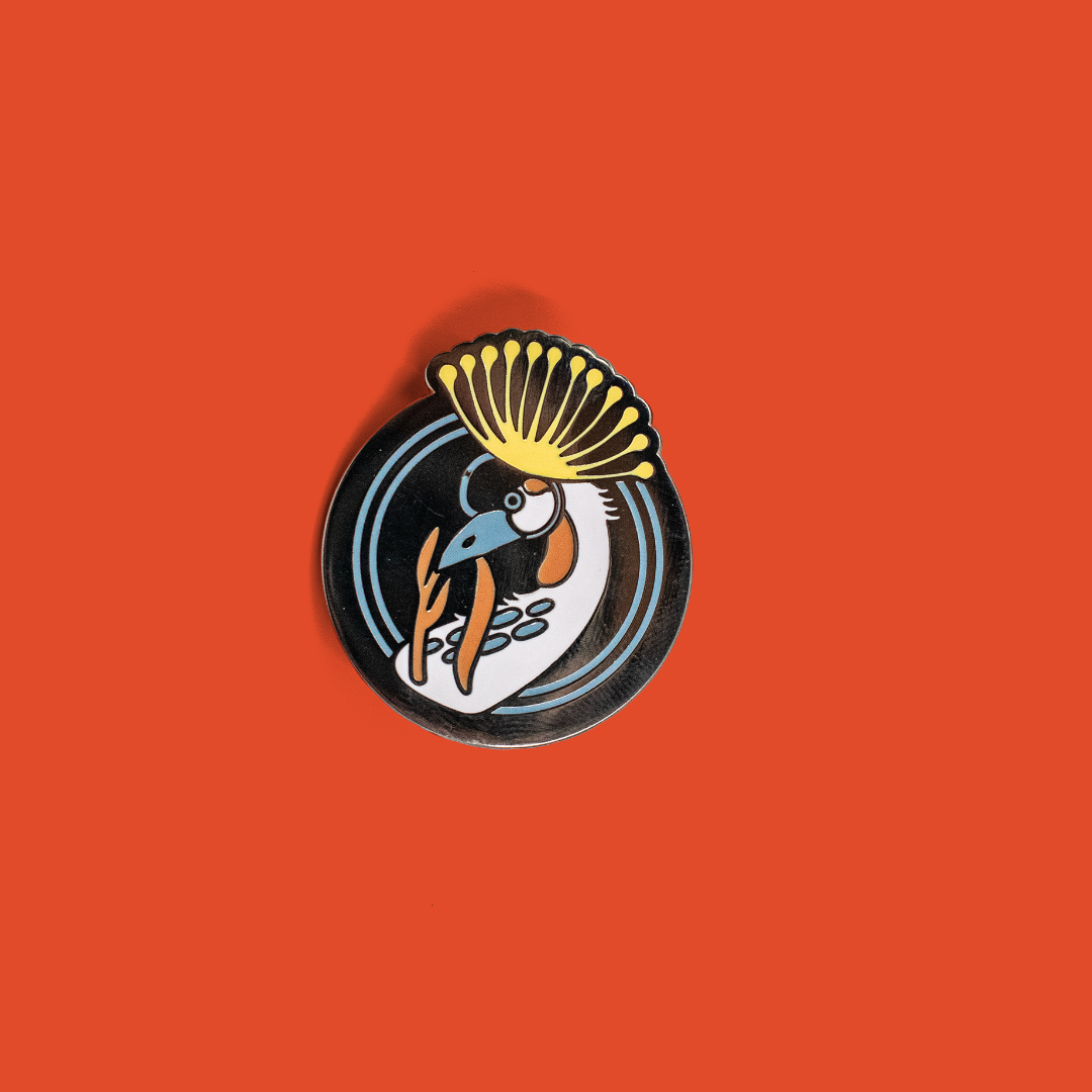 Closeup of enamel pin depicting a crowned crane.