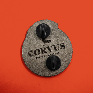 Details of backside of enamel pin showing pinbacks and Corvus Coffee Roasters logo.