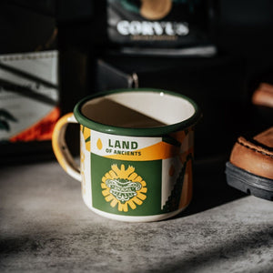 Specialty Coffee Roasters Camp Mug designed by Zaine Vaun depicting Quetzalcoatl in lifestyle setting.