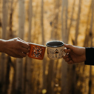 hands cheersing with cups outside with trees in background.