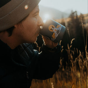 Specialty Coffee Roasters Camp Mug designed by Zaine Vaun depicting a crowned crane being drank by a man outside.